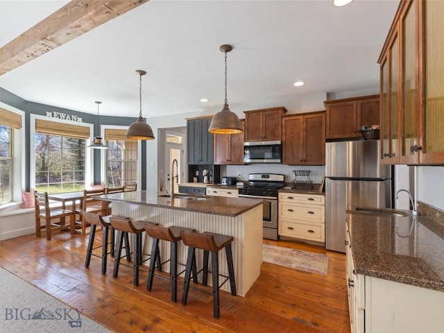 kitchen with sink, hanging light fixtures, a center island with sink, appliances with stainless steel finishes, and a kitchen breakfast bar