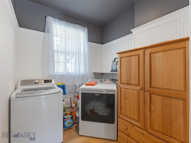 laundry area with cabinets, a healthy amount of sunlight, washer and dryer, and light wood-type flooring