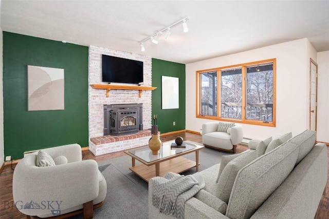 living room with dark hardwood / wood-style floors, rail lighting, and a brick fireplace