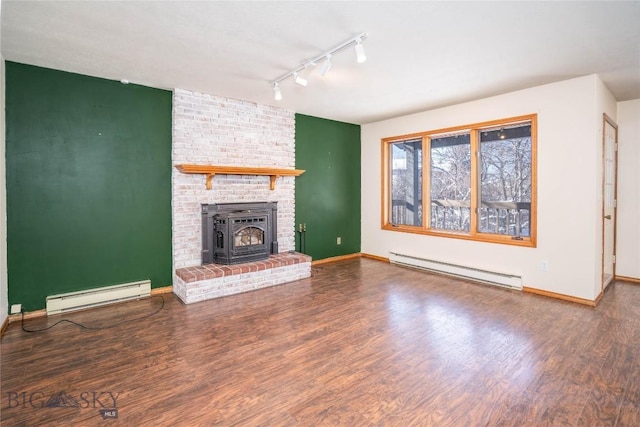 unfurnished living room featuring a brick fireplace, track lighting, dark hardwood / wood-style floors, and baseboard heating