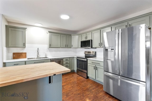 kitchen with wood counters, sink, tasteful backsplash, and appliances with stainless steel finishes