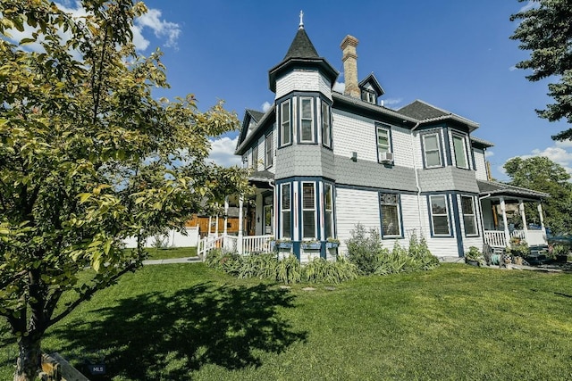 back of property featuring cooling unit, a yard, and covered porch