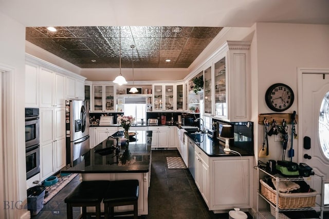 kitchen with appliances with stainless steel finishes, hanging light fixtures, a kitchen breakfast bar, a center island, and white cabinets