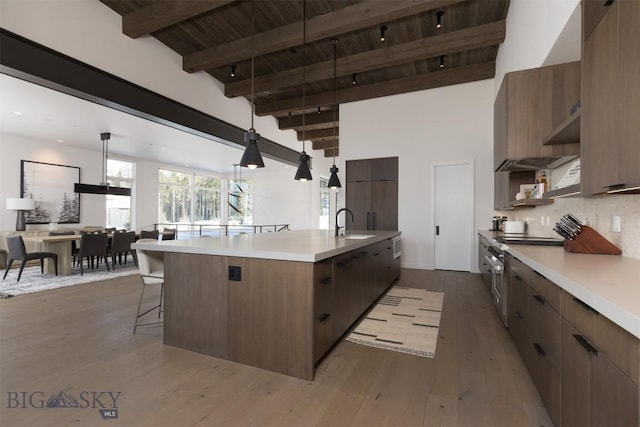 kitchen with pendant lighting, beamed ceiling, decorative backsplash, a large island, and wooden ceiling