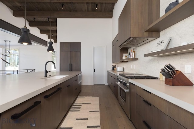 kitchen featuring beam ceiling, sink, high end range, and decorative light fixtures