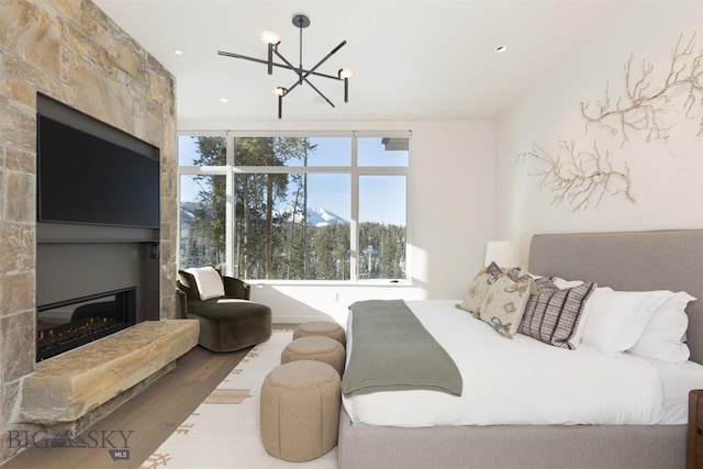 bedroom with hardwood / wood-style flooring, a fireplace, and a chandelier