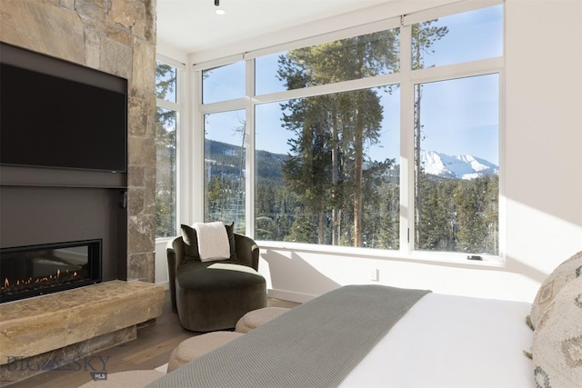 bedroom with a mountain view, a large fireplace, and hardwood / wood-style floors