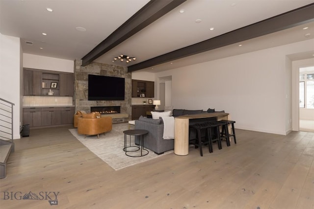 living room with a fireplace, beam ceiling, and light hardwood / wood-style floors