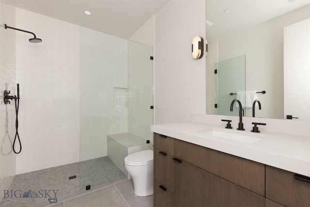 bathroom with vanity, toilet, tile patterned flooring, and a tile shower