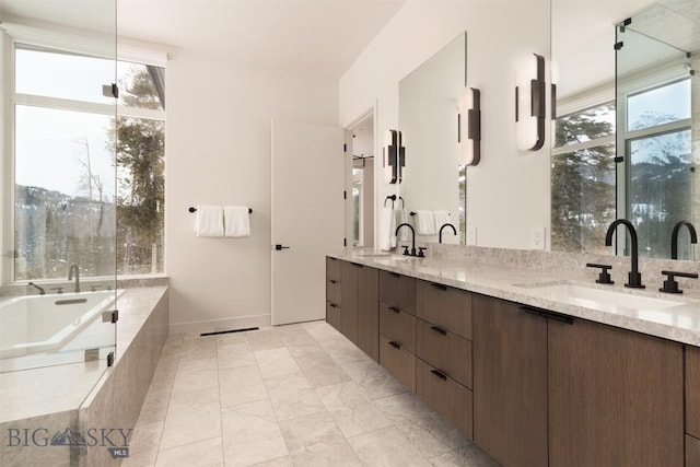 bathroom featuring vanity, a healthy amount of sunlight, and a relaxing tiled tub