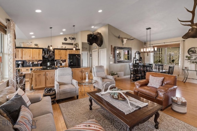 living room featuring lofted ceiling, an inviting chandelier, and light hardwood / wood-style floors