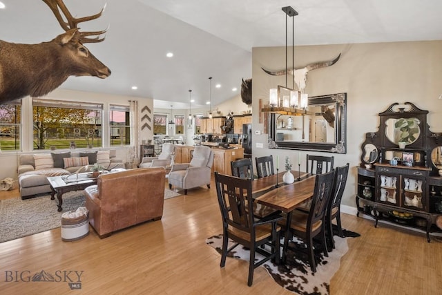 dining area featuring high vaulted ceiling, a notable chandelier, and light wood-type flooring