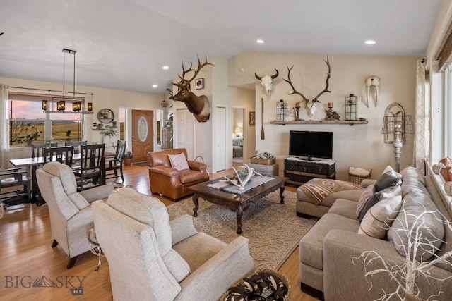 living room with plenty of natural light, vaulted ceiling, and light wood-type flooring