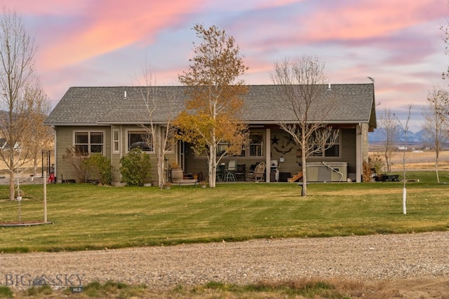 back house at dusk featuring a yard