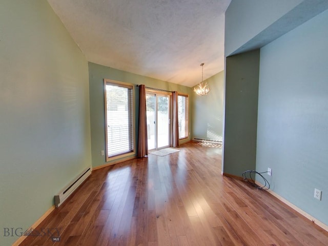 unfurnished room with hardwood / wood-style flooring, lofted ceiling, an inviting chandelier, and baseboard heating