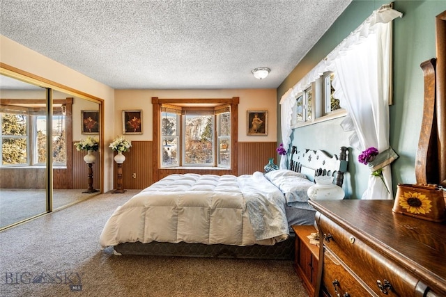 bedroom featuring a closet, wood walls, a textured ceiling, and carpet