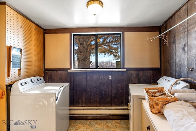 laundry area with a baseboard heating unit, wooden walls, and washer and dryer