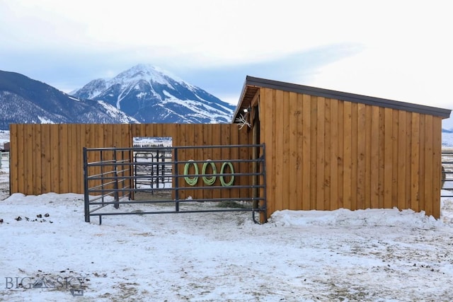 snow covered gate with a mountain view and an outdoor structure