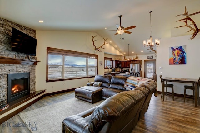 living room with ceiling fan, a stone fireplace, high vaulted ceiling, and dark hardwood / wood-style flooring