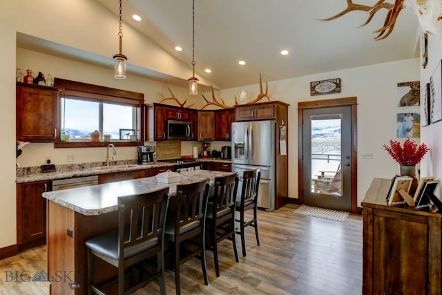 kitchen with lofted ceiling, a breakfast bar, a center island, pendant lighting, and stainless steel appliances