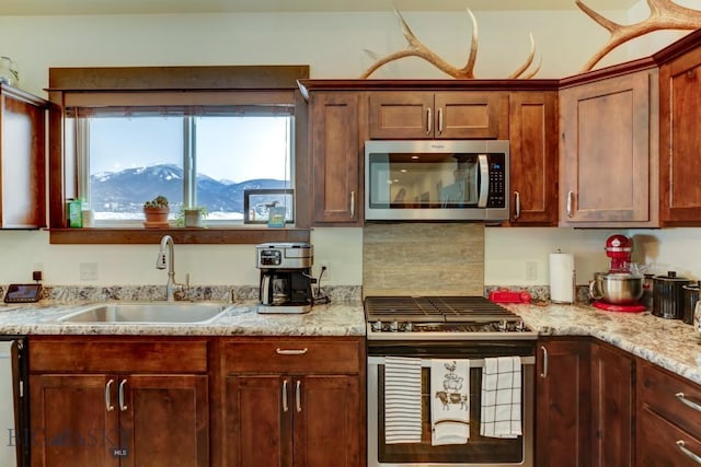 kitchen with stainless steel appliances, a mountain view, sink, and light stone counters