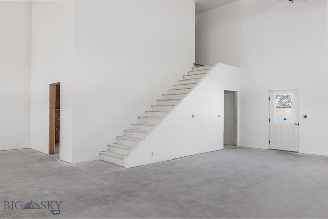 stairs featuring a high ceiling and concrete flooring