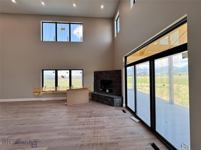 6111 Springhill Rd, Belgrade, MT 59714 - unfurnished living room with light wood-type flooring, a fireplace, recessed lighting, a towering ceiling, and baseboards
