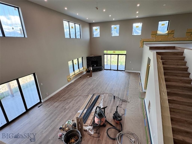 6111 Springhill Rd, Belgrade, MT 59714 - unfurnished living room with recessed lighting, wood finished floors, baseboards, a high ceiling, and stairs