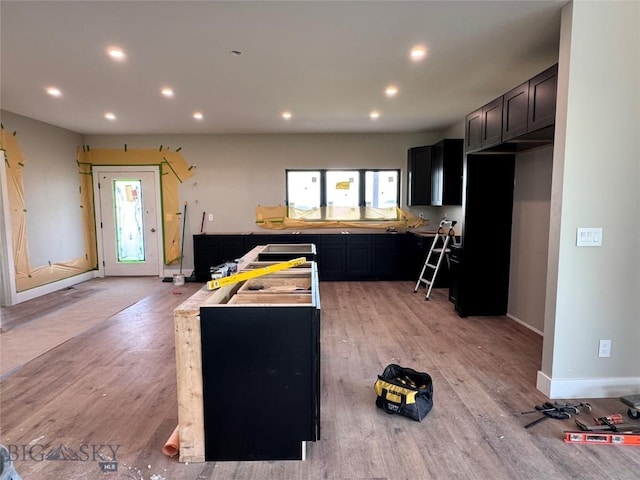 6111 Springhill Rd, Belgrade, MT 59714 - kitchen with light wood-type flooring, recessed lighting, baseboards, dark cabinets, and a center island