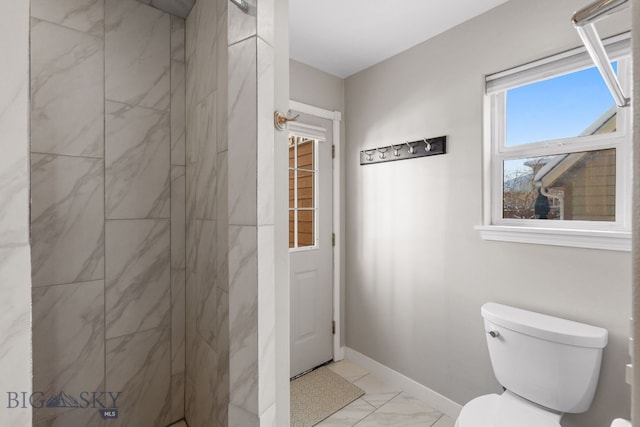 bathroom featuring a tile shower and toilet