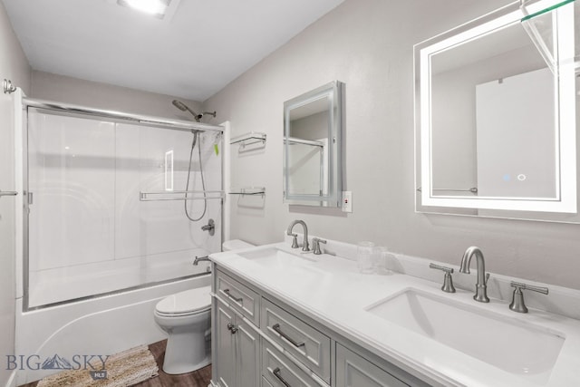 full bathroom featuring vanity, bath / shower combo with glass door, and toilet