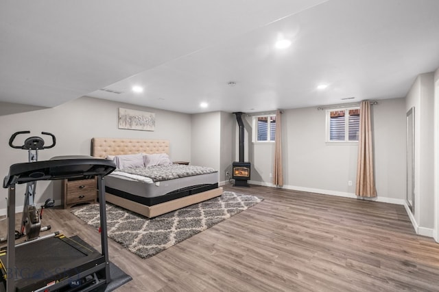 bedroom with a wood stove and light hardwood / wood-style floors