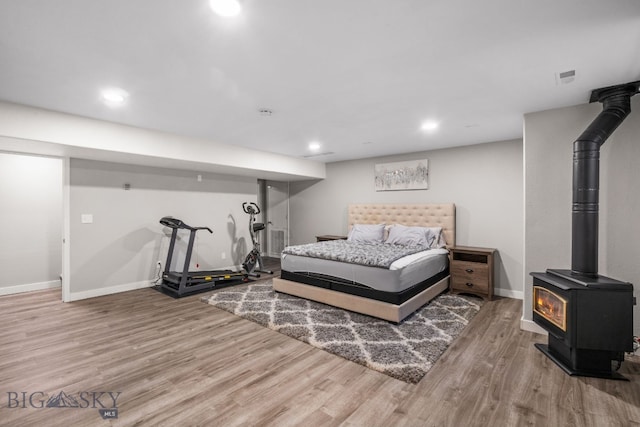 bedroom featuring hardwood / wood-style floors and a wood stove