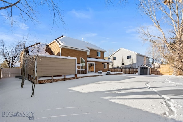 snow covered back of property featuring a shed