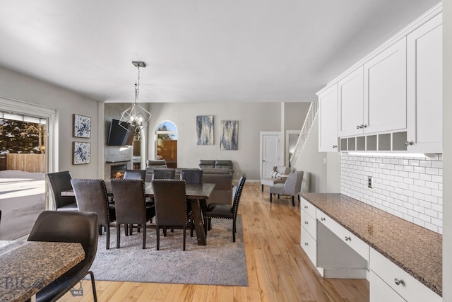 dining area with an inviting chandelier, a fireplace, and light hardwood / wood-style floors