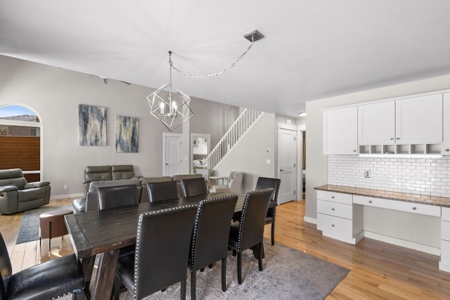 dining space featuring built in desk, an inviting chandelier, and light wood-type flooring