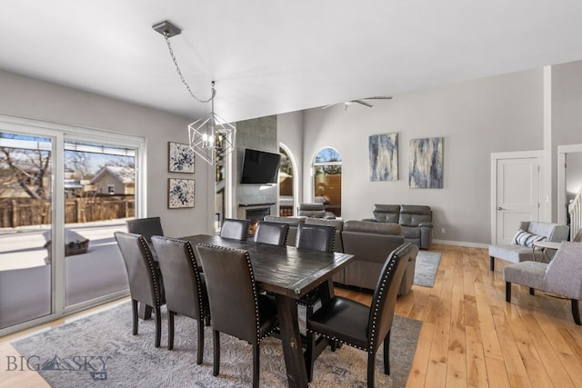 dining room with a chandelier, a fireplace, and light hardwood / wood-style flooring