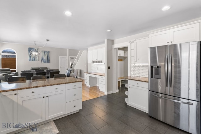 kitchen featuring white cabinetry, decorative light fixtures, dark stone counters, and stainless steel fridge with ice dispenser