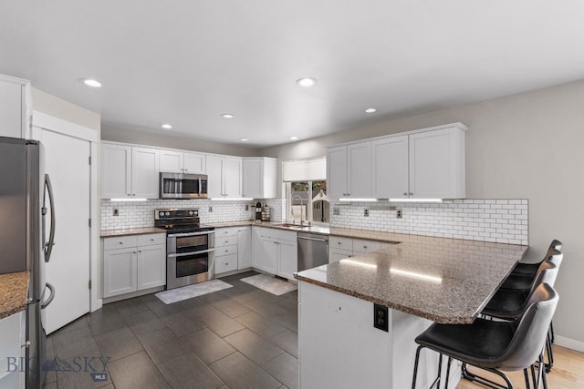 kitchen with white cabinetry, a breakfast bar, appliances with stainless steel finishes, and kitchen peninsula