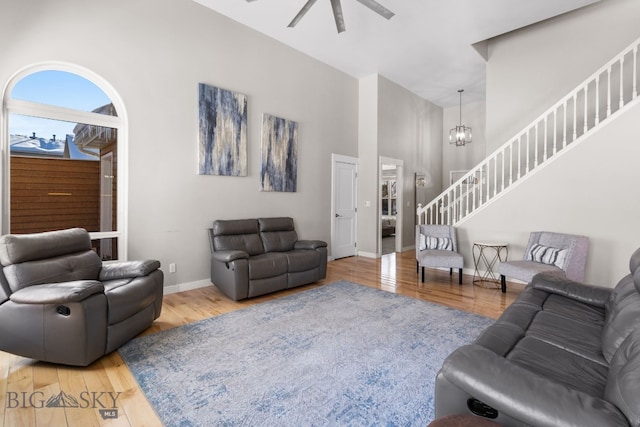 living room featuring a high ceiling, ceiling fan with notable chandelier, and hardwood / wood-style floors