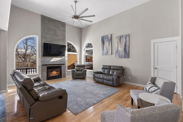 living room with a towering ceiling, a fireplace, and light hardwood / wood-style floors