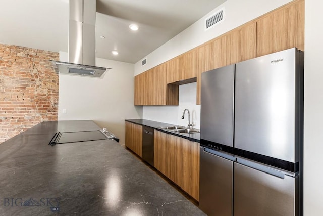 kitchen with brick wall, island exhaust hood, appliances with stainless steel finishes, and sink