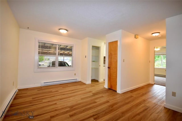 spare room with light wood-type flooring and a baseboard heating unit