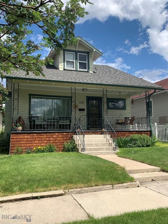 view of front of house with covered porch and a front lawn