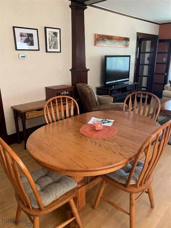 dining space with decorative columns and light wood-type flooring