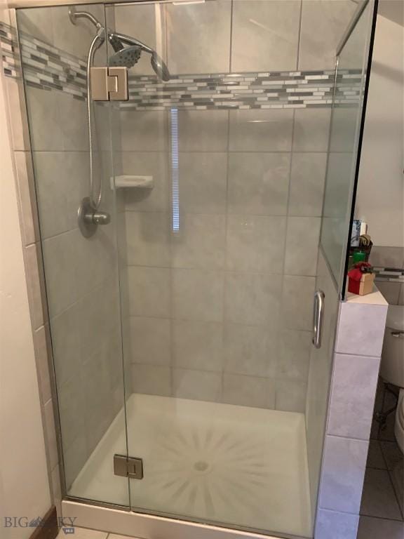 bathroom featuring an enclosed shower, tile patterned flooring, and toilet