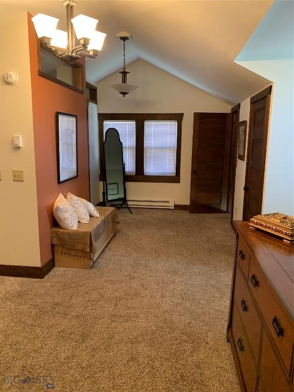 interior space with light carpet, a notable chandelier, lofted ceiling, and a baseboard heating unit