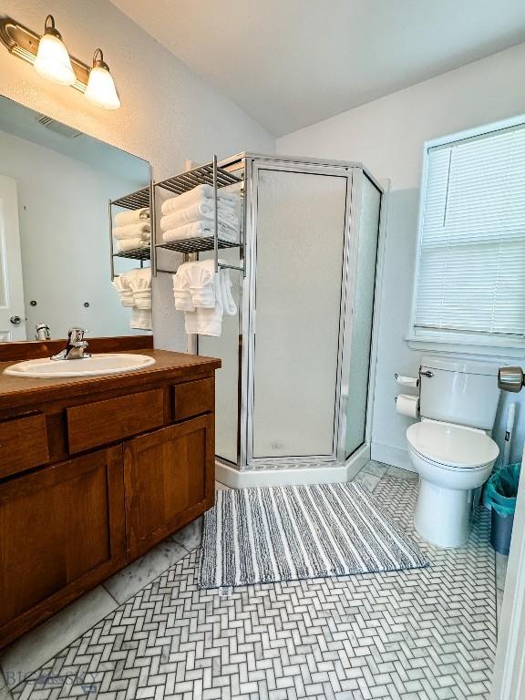 bathroom featuring vanity, toilet, a shower with shower door, and tile patterned flooring