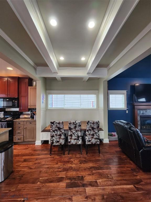 kitchen featuring a fireplace, beamed ceiling, dark hardwood / wood-style flooring, black appliances, and crown molding