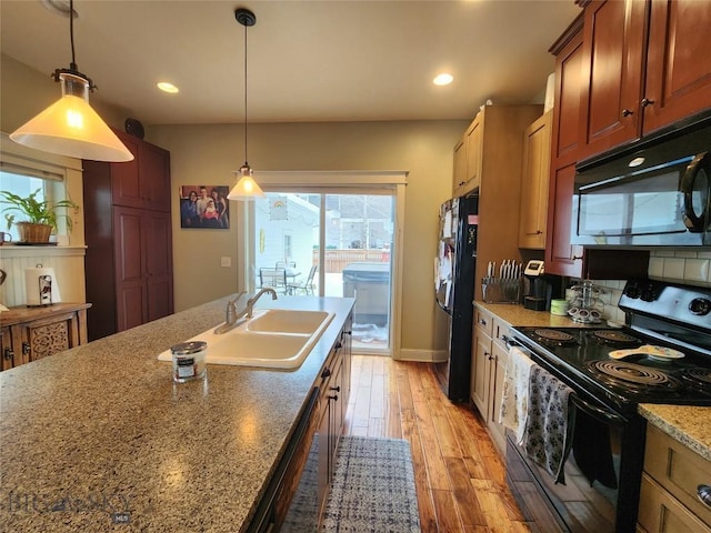 kitchen with sink, light stone counters, hanging light fixtures, light wood-type flooring, and black appliances